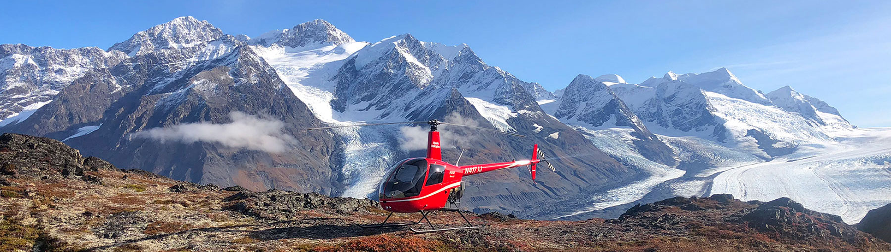 Helicopter landed in front of majestic, Alaskan mountain.