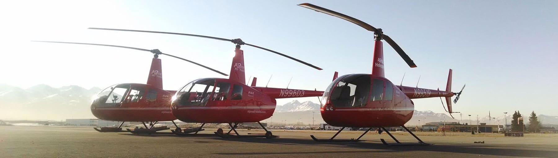 Three Robinson helicopters on the ground at the airport.